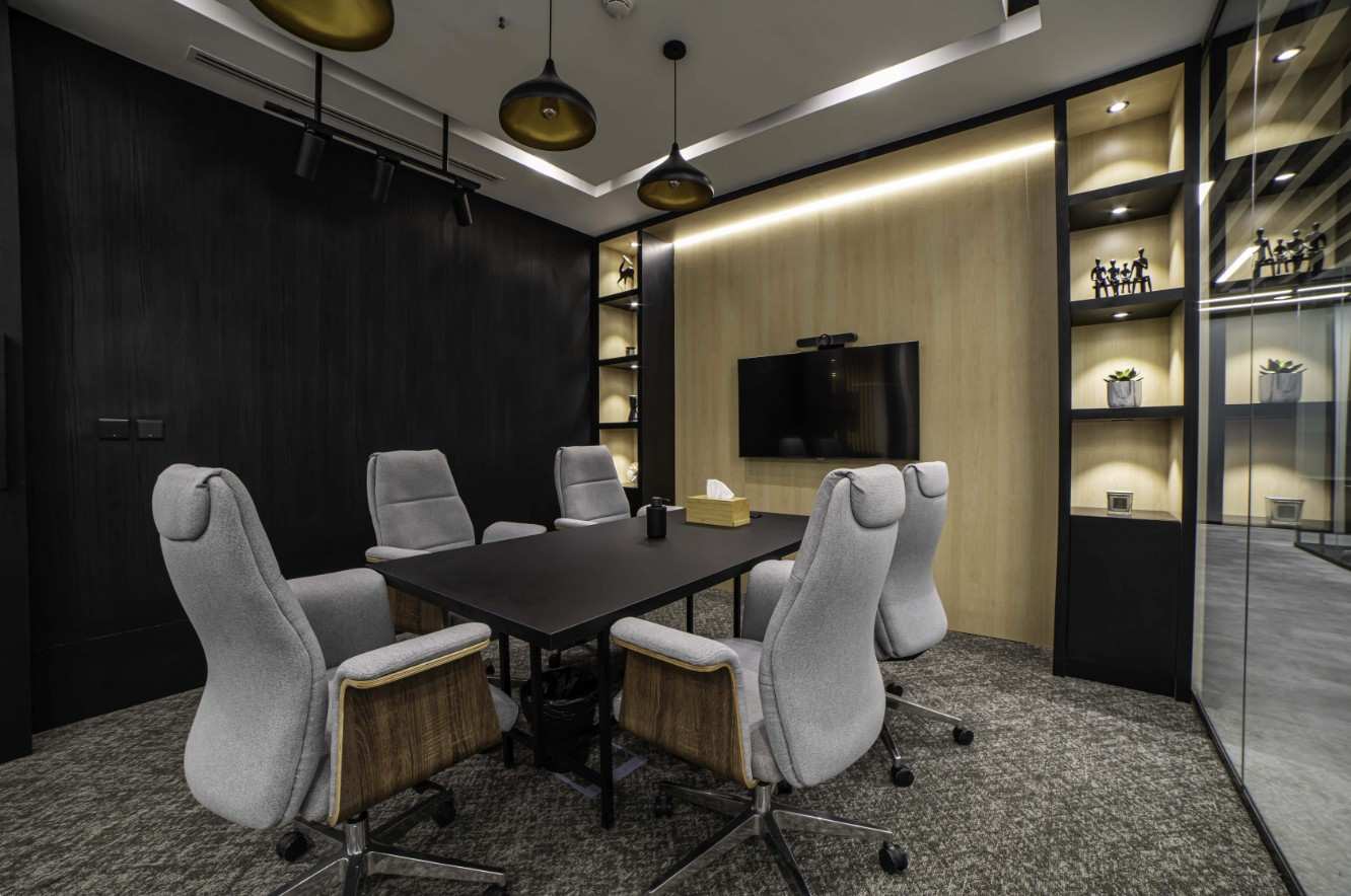 Modern conference room featuring a sleek black table, ergonomic gray chairs, and a wall-mounted TV, designed for efficient office renovations by Hausfit in Dubai.