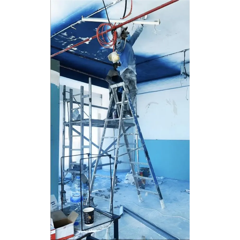 Worker on ladder applying professional ceiling paint in an office renovation, showcasing modern design elements and preparation for electrical integration.