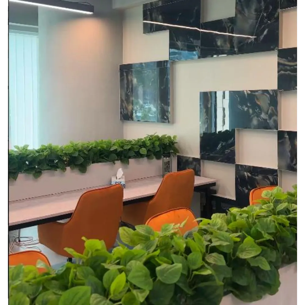 Modern office interior featuring sleek design with orange chairs, a green plant border, and reflective wall panels, showcasing Hausfit&rsquo;s innovative renovation expertise.
